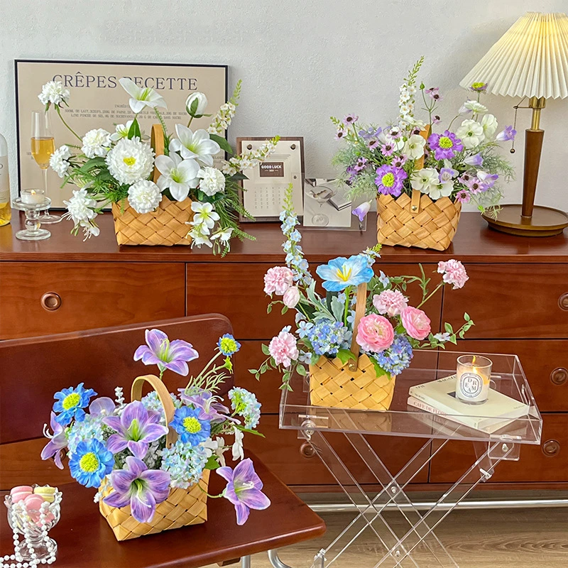 Artificial flower basket arrangement in a woven basket with an upright handle, styled in a room setting