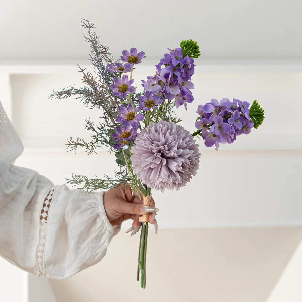Violet artificial mini flower bouquet of three or four stems tied at the base, held in one hand