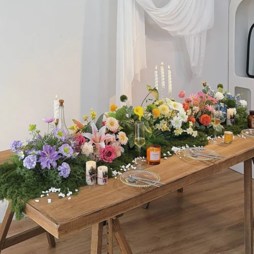 Artificial round table centrepiece on a moss-covered base, finished on all sides, styled in a room setting
