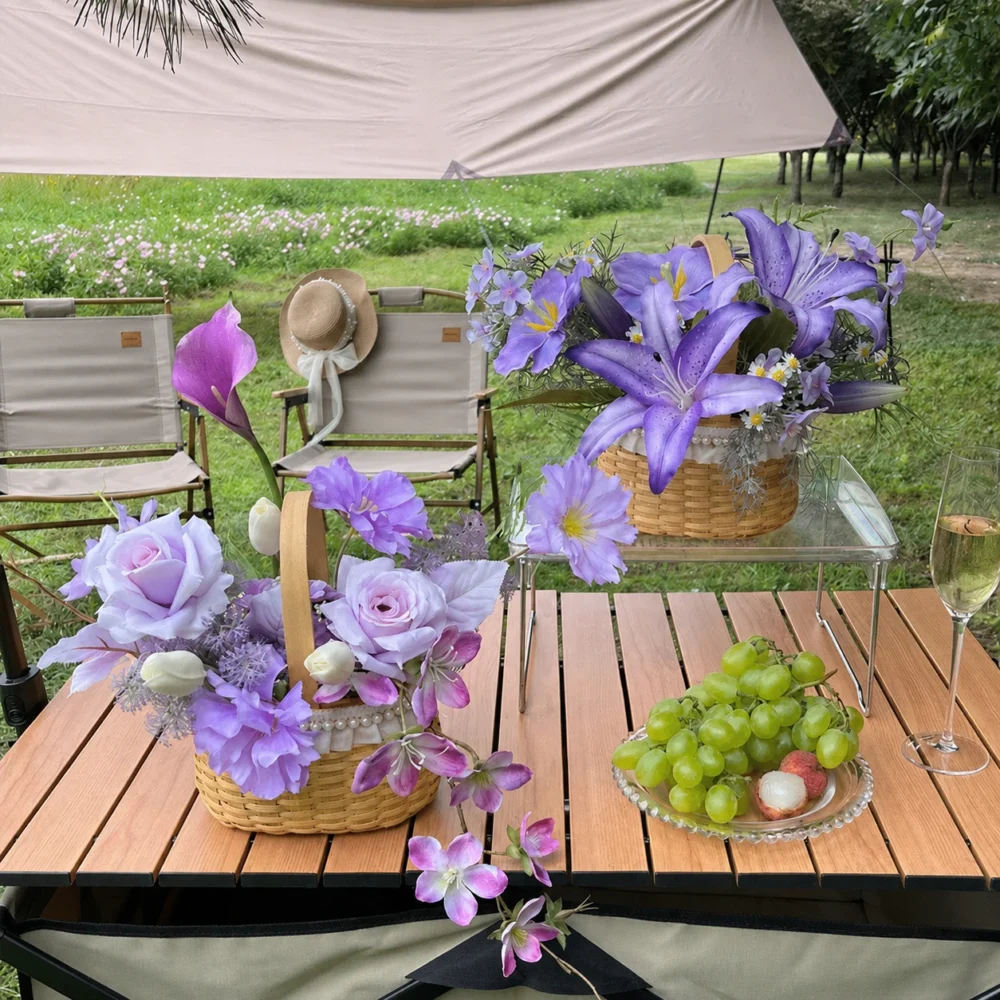 Purple clematis artificial summer flower basket in a round cane basket with an upright handle, styled in a room setting
