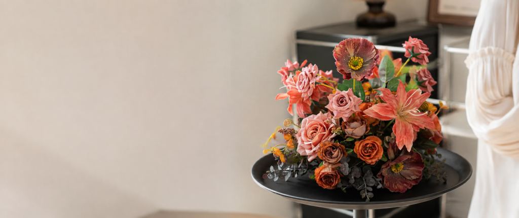 Terracotta and pink faux flower arrangement on a black tray table in a modern home setting