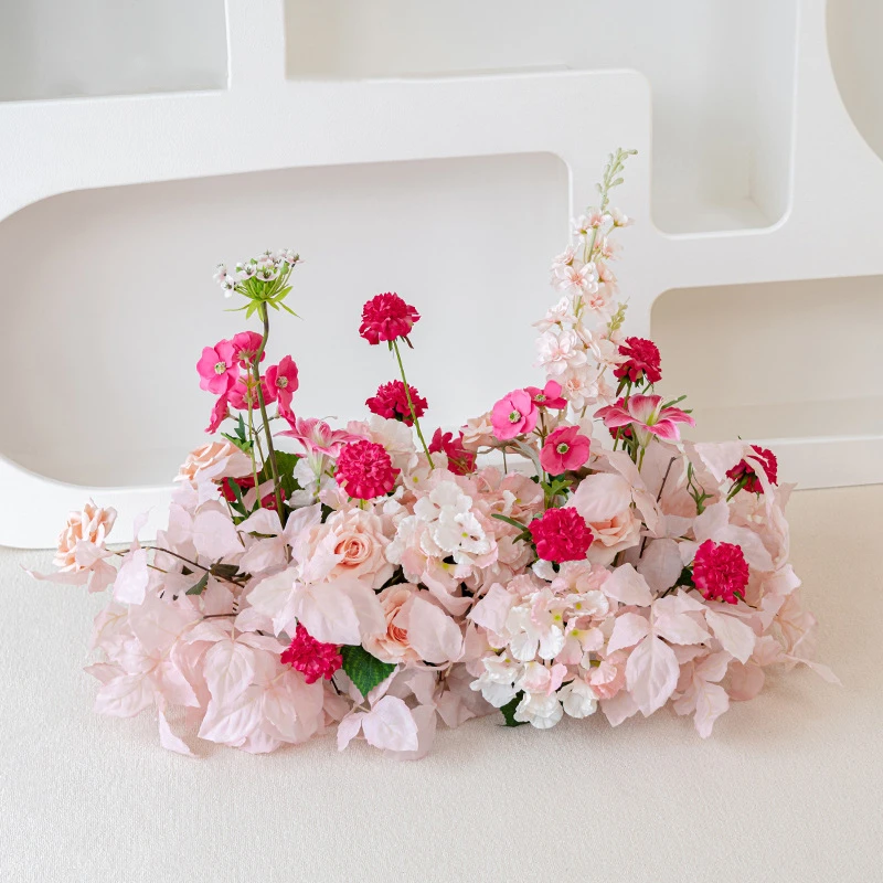Pink artificial wedding arch arrangement built long and low as a one-sided run, styled on a table top