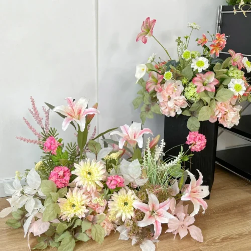 Artificial wedding arch arrangement built long and low as a one-sided run, styled in a room setting