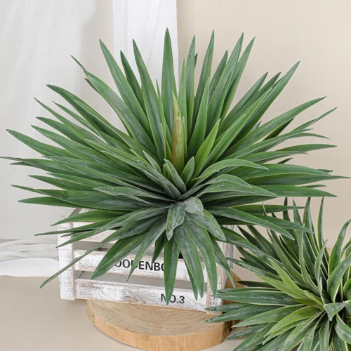 Broad green artificial agave rosette as a flat radiating rosette on a short spike, styled in a room setting