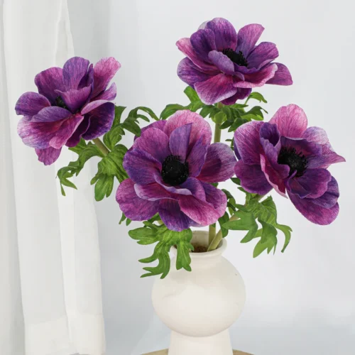 Purple artificial anemone stem with a black velvet centre inside crinkled petals, arranged in a vase