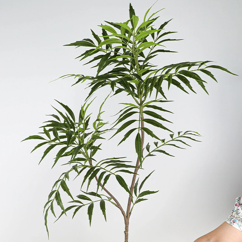 Full branch artificial bamboo stem with narrow leaves layered along a jointed cane, styled in a room setting