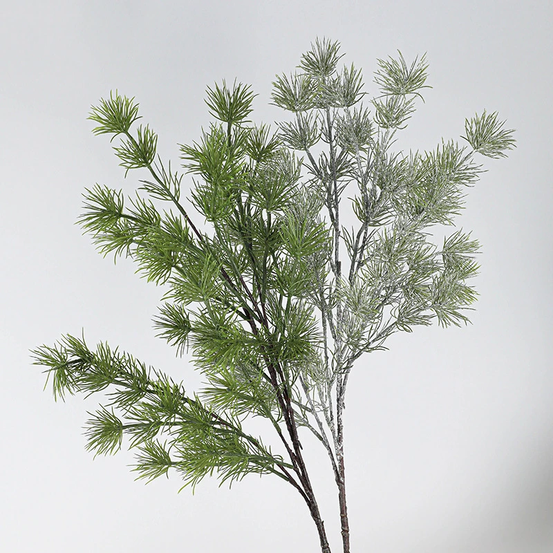 Green beside frosted artificial Christmas foliage spray