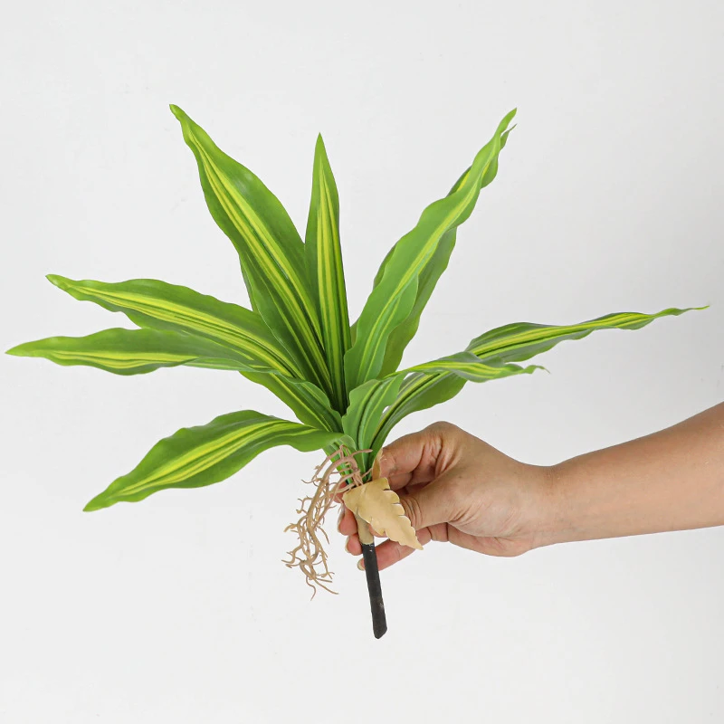 Held artificial dracaena leaf cluster with aerial roots left on so it plants straight into a pot, held in one hand