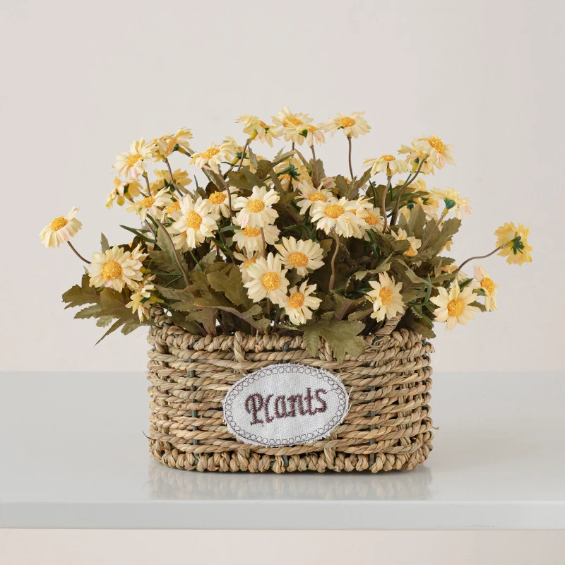 Yellow daisy artificial flower basket, oval woven in an oval woven basket with a ceramic tag, styled on a table top