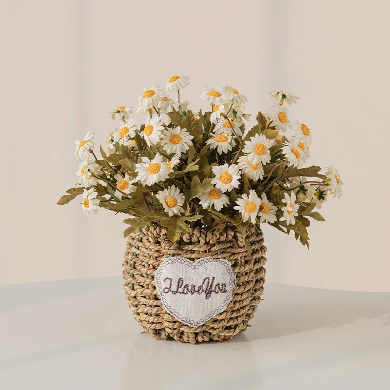White daisy artificial flower gift basket in a round woven basket with a heart-shaped tag, styled on a table top