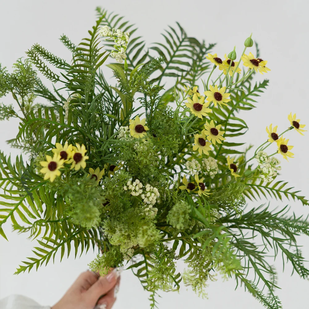 Yellow sunflower artificial greenery bunch of mixed ferns, eucalyptus and berry stems, held in one hand