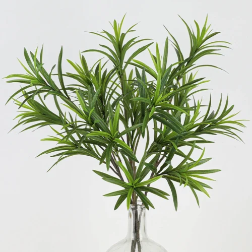 Massed artificial greenery stem of narrow lance leaves set in dense whorls, arranged in a vase