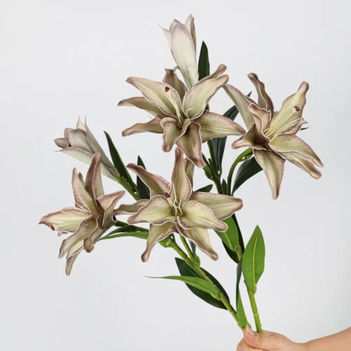 Antique taupe artificial lily stem carrying two open flowers and one closed bud, held in one hand