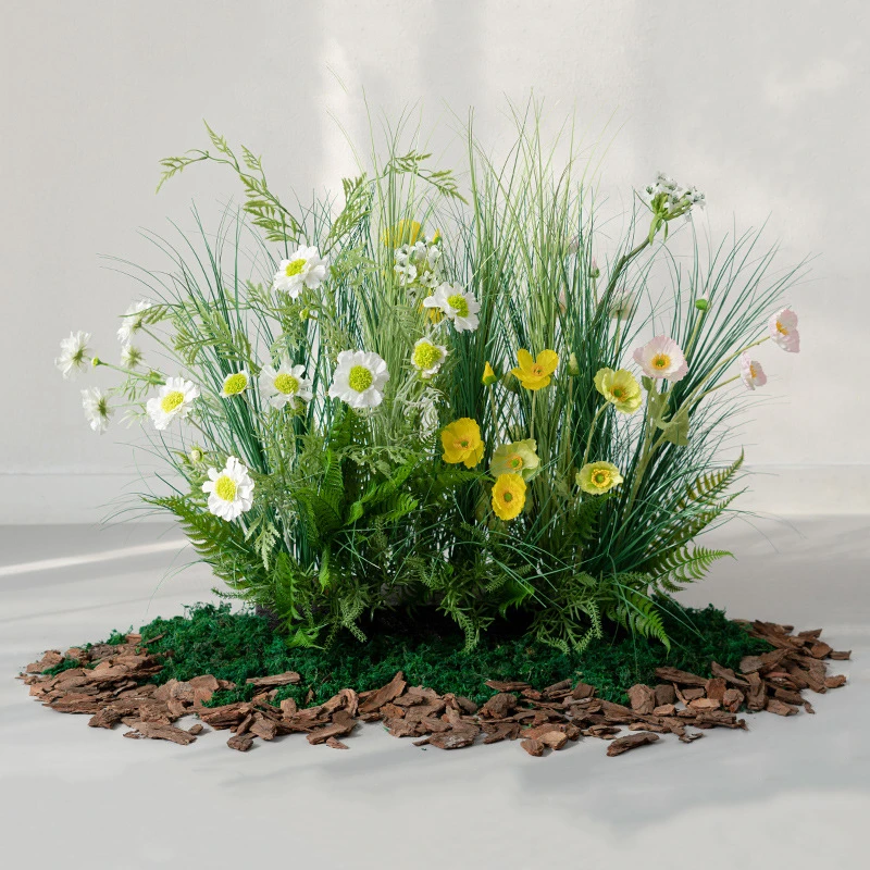 Yellow daisy artificial ornamental grass border on a bark and moss base