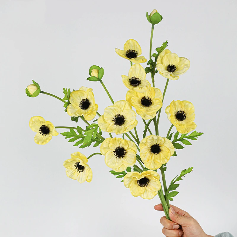 Lemon yellow, a bunch artificial poppy spray carrying four open flowers and a bud on one stem, held in one hand