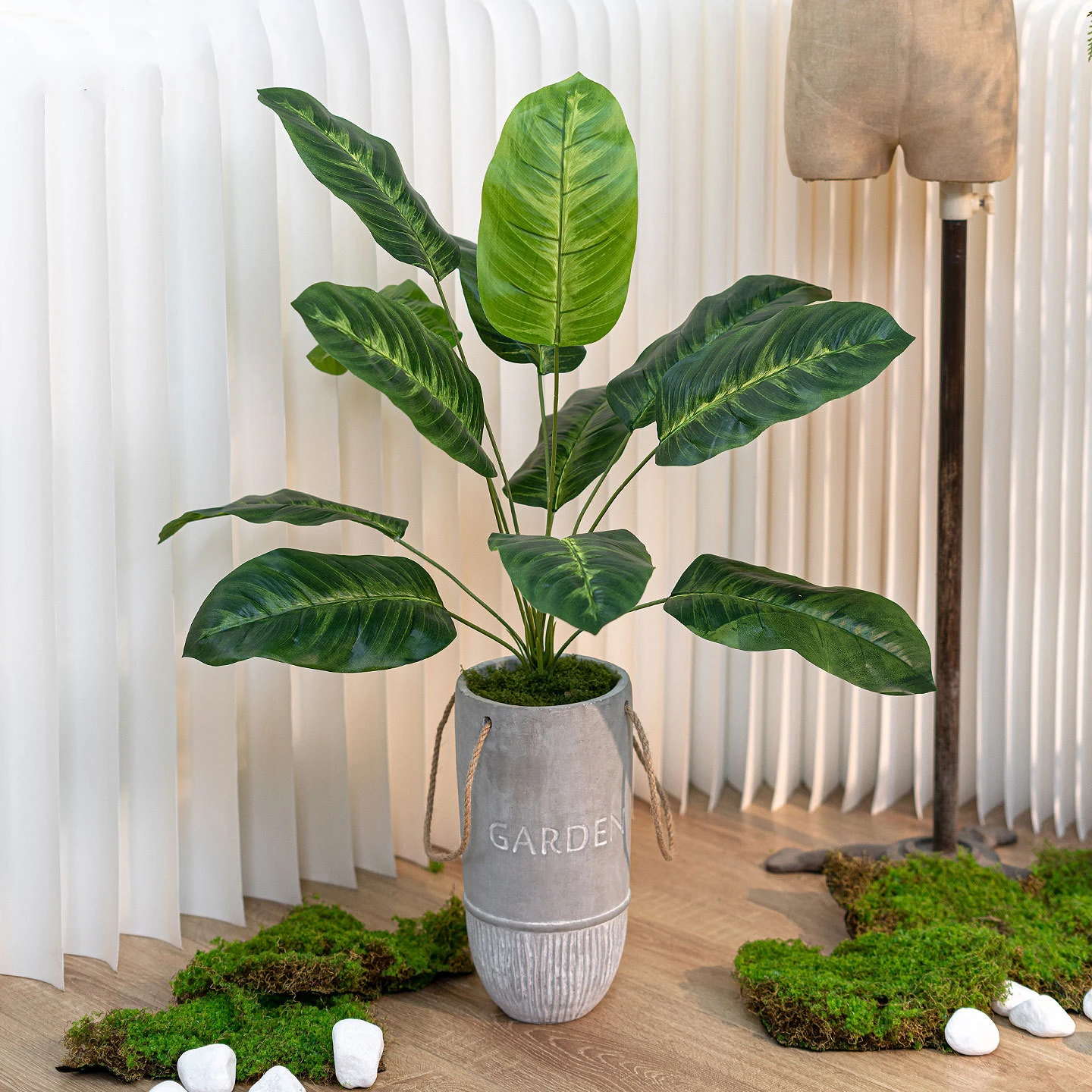 Banana leaf artificial potted plant in a cement pot in a grey cement pot with rope handles, styled in a room setting