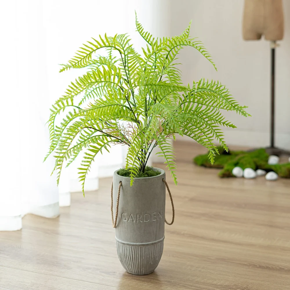 Bright green fern artificial potted plant in a cement pot in a grey cement pot with rope handles, styled in a room setting