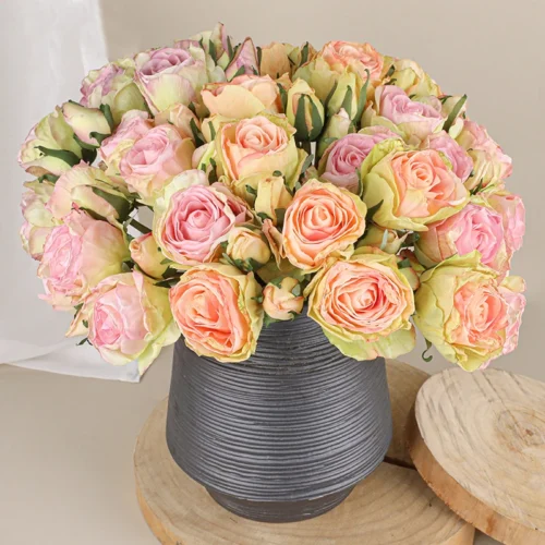 Pink and peach, in a grey jug artificial rose posy of twelve roses tied at the stem with raffia, arranged in a vase