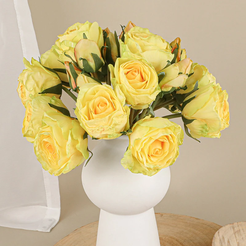 Yellow, in a white vase artificial rose posy of twelve roses tied at the stem with raffia, arranged in a vase