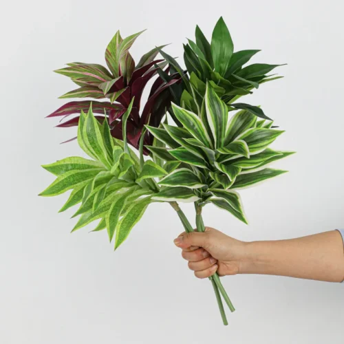 Lime, burgundy and green together artificial tropical leaf bush of patterned leaves gathered on one short stalk, held in one hand