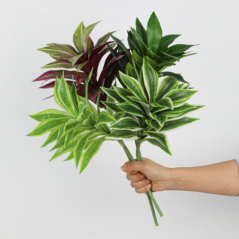 Lime, burgundy and green together artificial tropical leaf bush of patterned leaves gathered on one short stalk, held in one hand