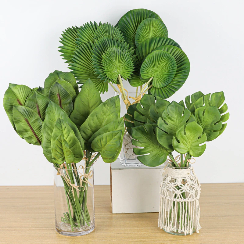 Mixed, in a vase artificial tropical leaf stems of fan palm, monstera and banana leaf, arranged in a vase