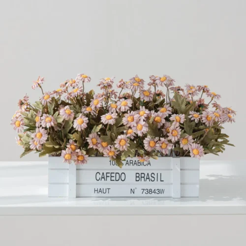 Apricot artificial window box of daisies packed into a stencilled coffee crate, styled on a table top