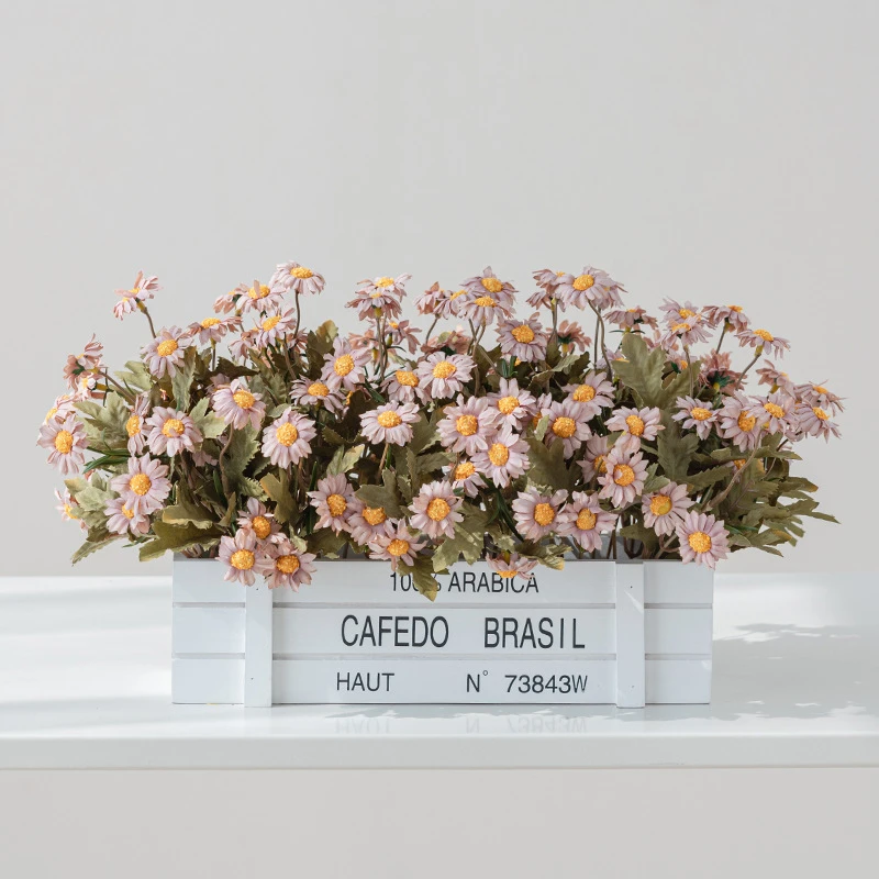 Apricot artificial window box of daisies packed into a stencilled coffee crate, styled on a table top