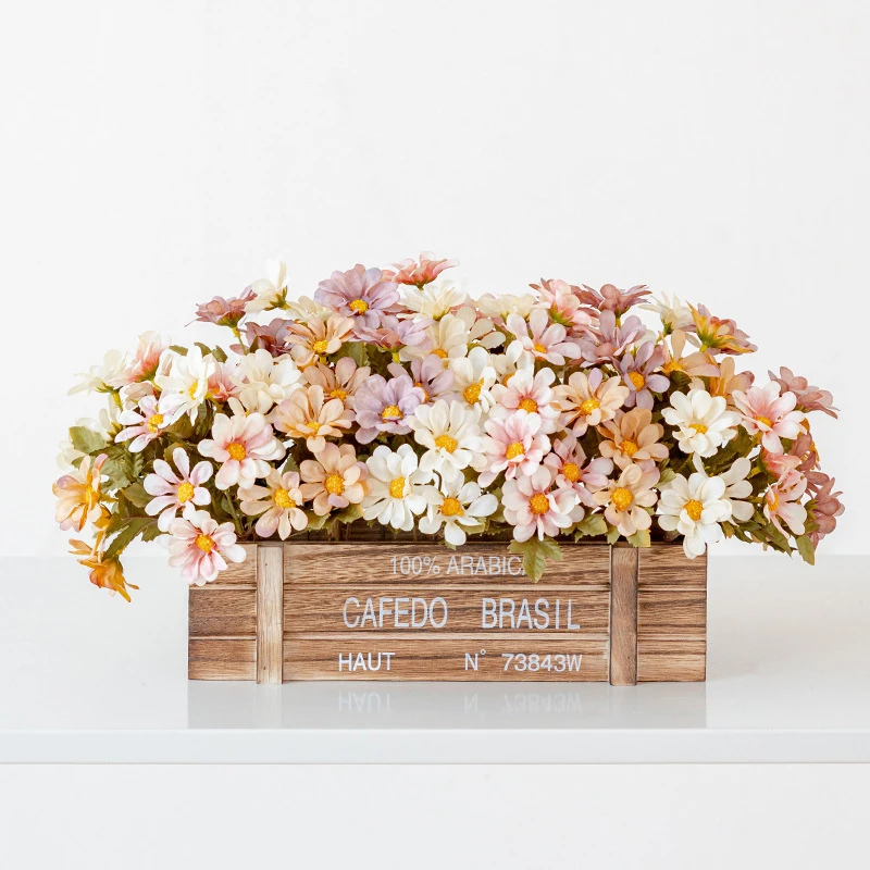 Peach artificial window box of daisies packed into a stencilled coffee crate, styled on a table top