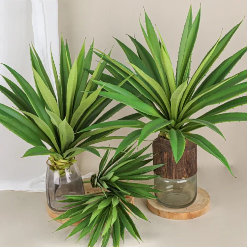 In a glass pot artificial yucca leaf head as a single sword-leaved head on a short stub, styled in a room setting