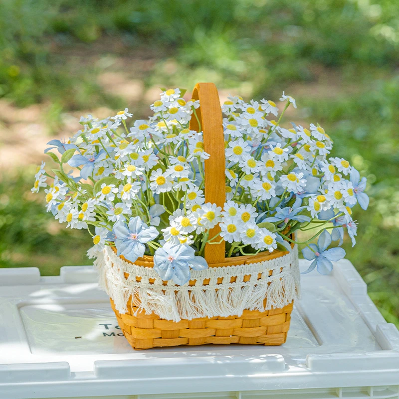 Blue and white artificial daisy basket massed in a woven cane basket, styled on a table top