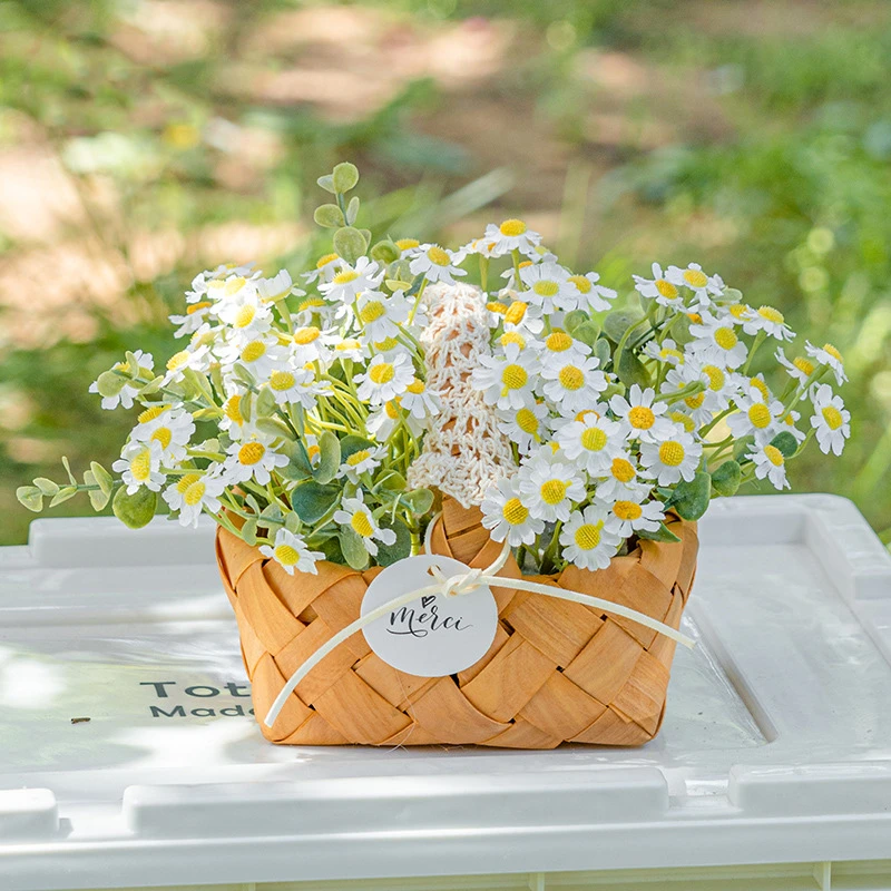 Ivory daisy artificial daisy basket massed in a woven cane basket, styled on a table top