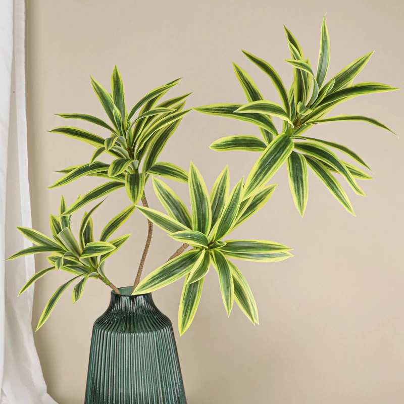 Yellow variegated, in a vase tall artificial leaf branch forking into three to five spiky leaf heads, arranged in a vase